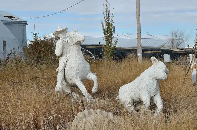 Cowboy and calf sculptures in tall grass